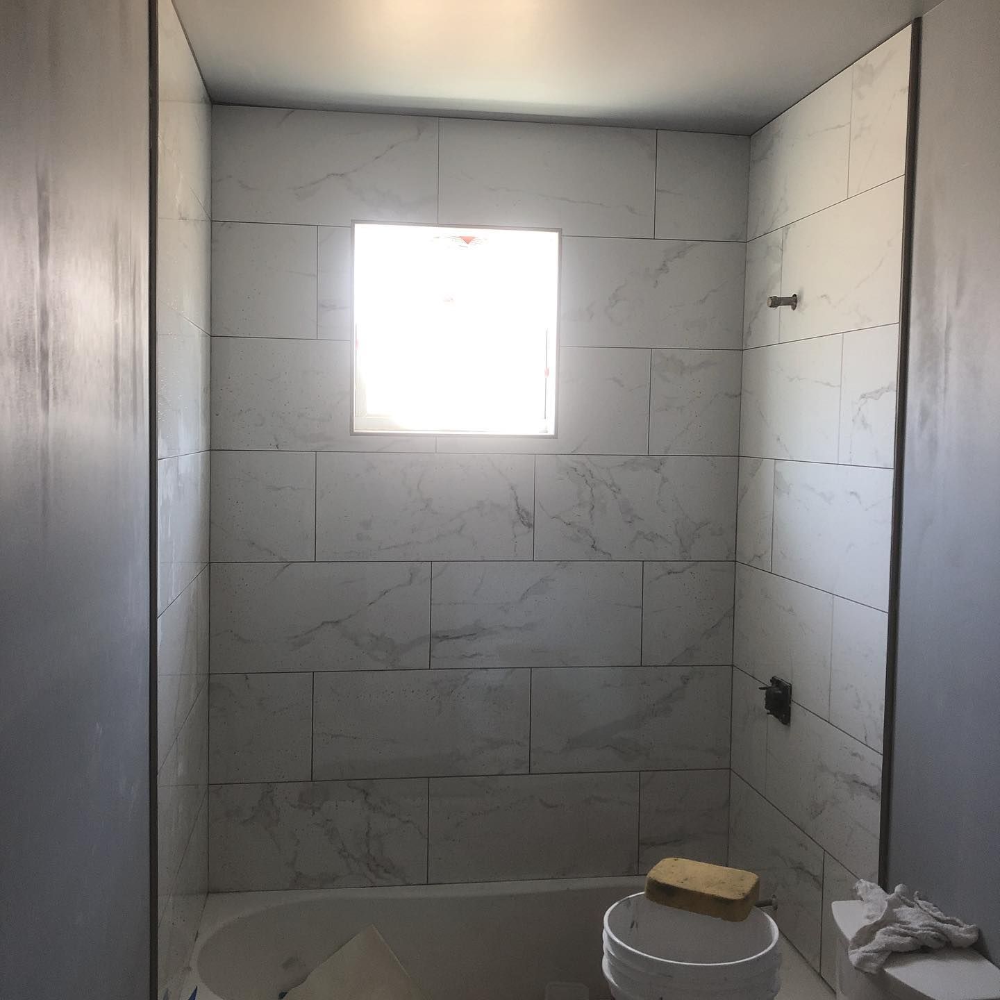 A bathroom with white tiles and a window