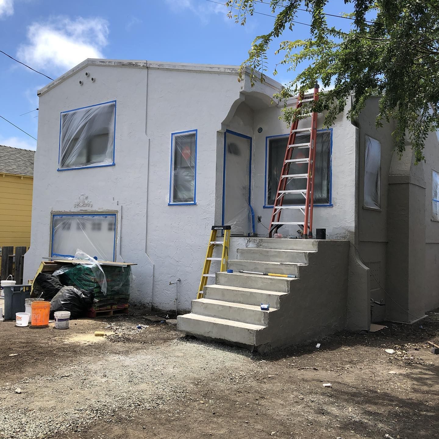 A white house with stairs and a ladder in front of it