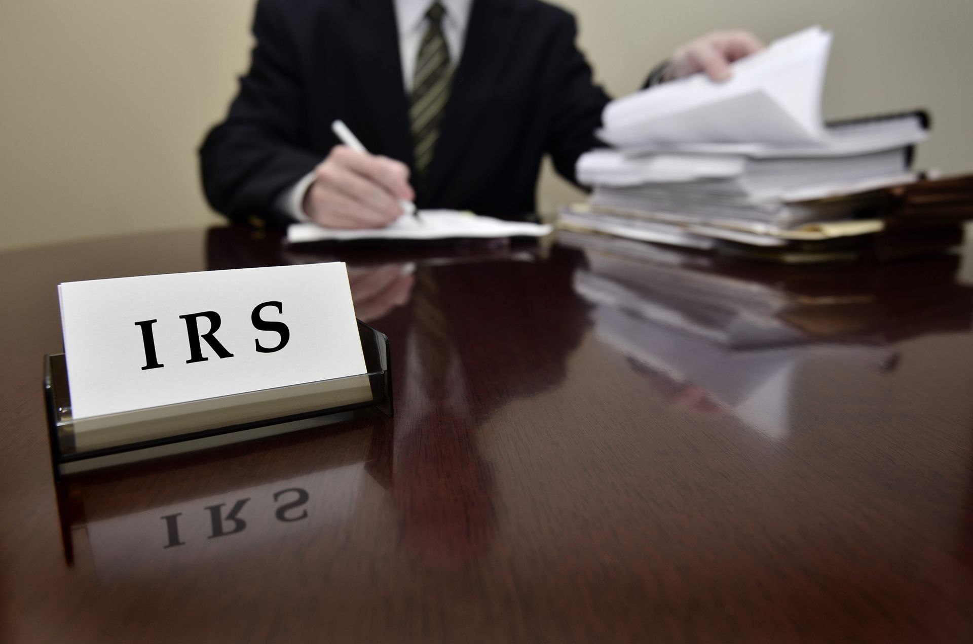 Person in suit writing at desk with