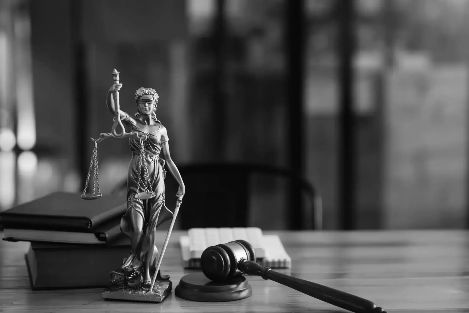 A statue of justice is sitting on a wooden table next to a judge 's gavel.