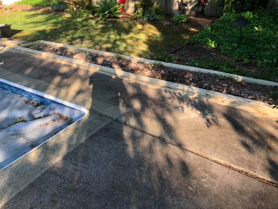 A concrete patio with a swimming pool in the background.