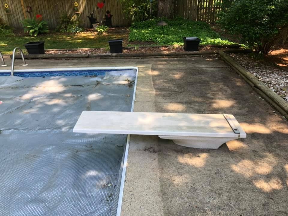 A diving board is sitting next to a swimming pool.