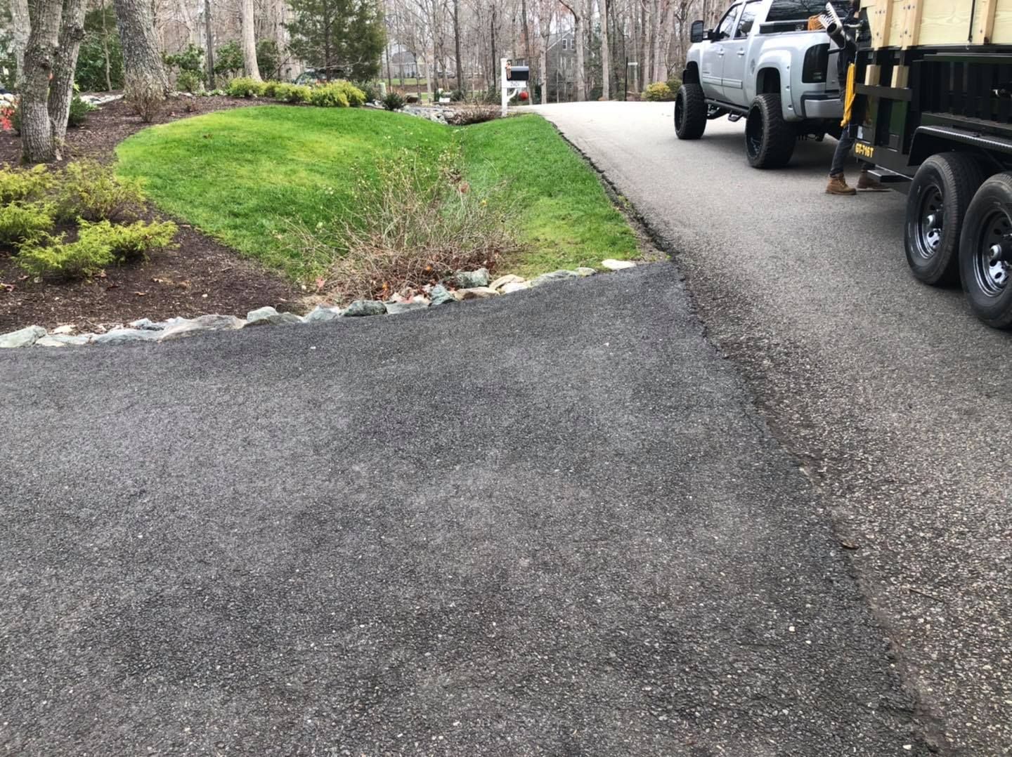 A truck is parked in a driveway next to a trailer.