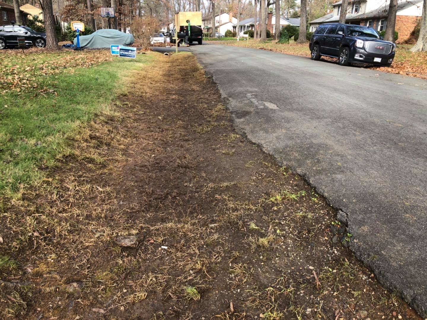 A car is parked on the side of the road next to a grassy area.