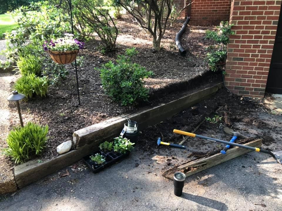 A bunch of gardening tools are laying on the ground in front of a brick building.