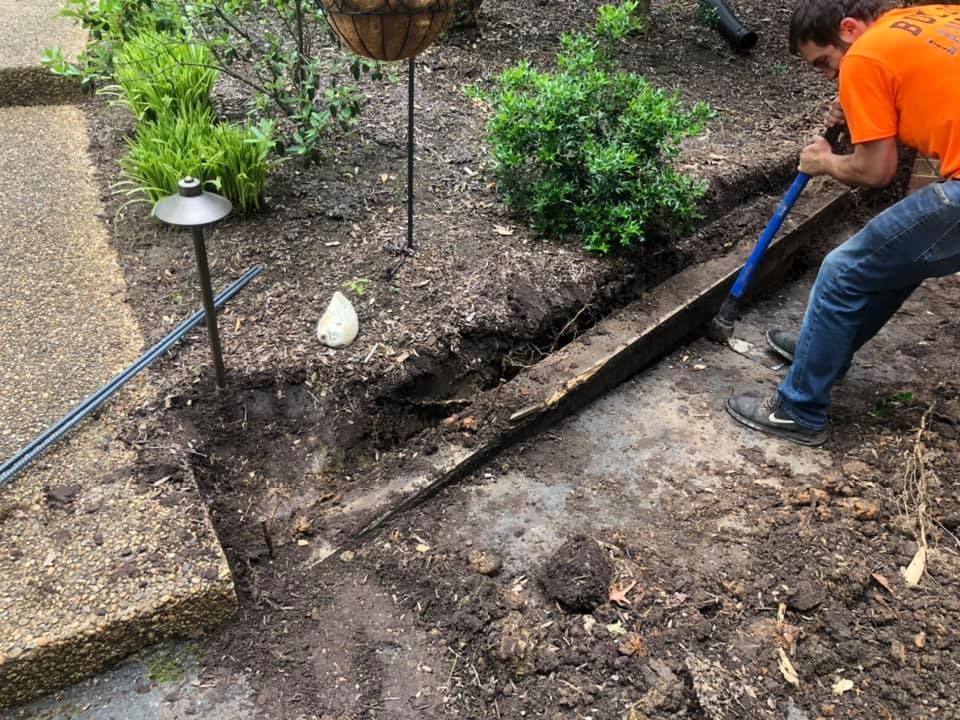 A man is digging a hole in the ground with a shovel.
