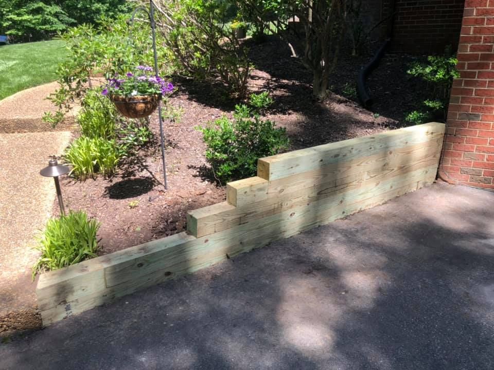 A wooden wall is being built in front of a brick house.