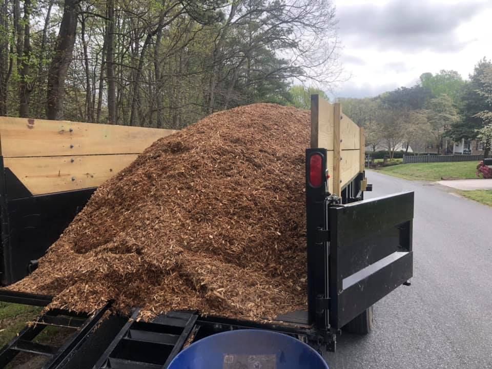 A pile of mulch is sitting on the back of a trailer.