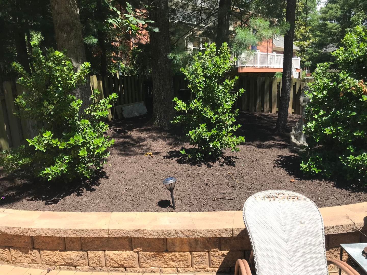 A white chair is sitting on a patio next to a brick wall.