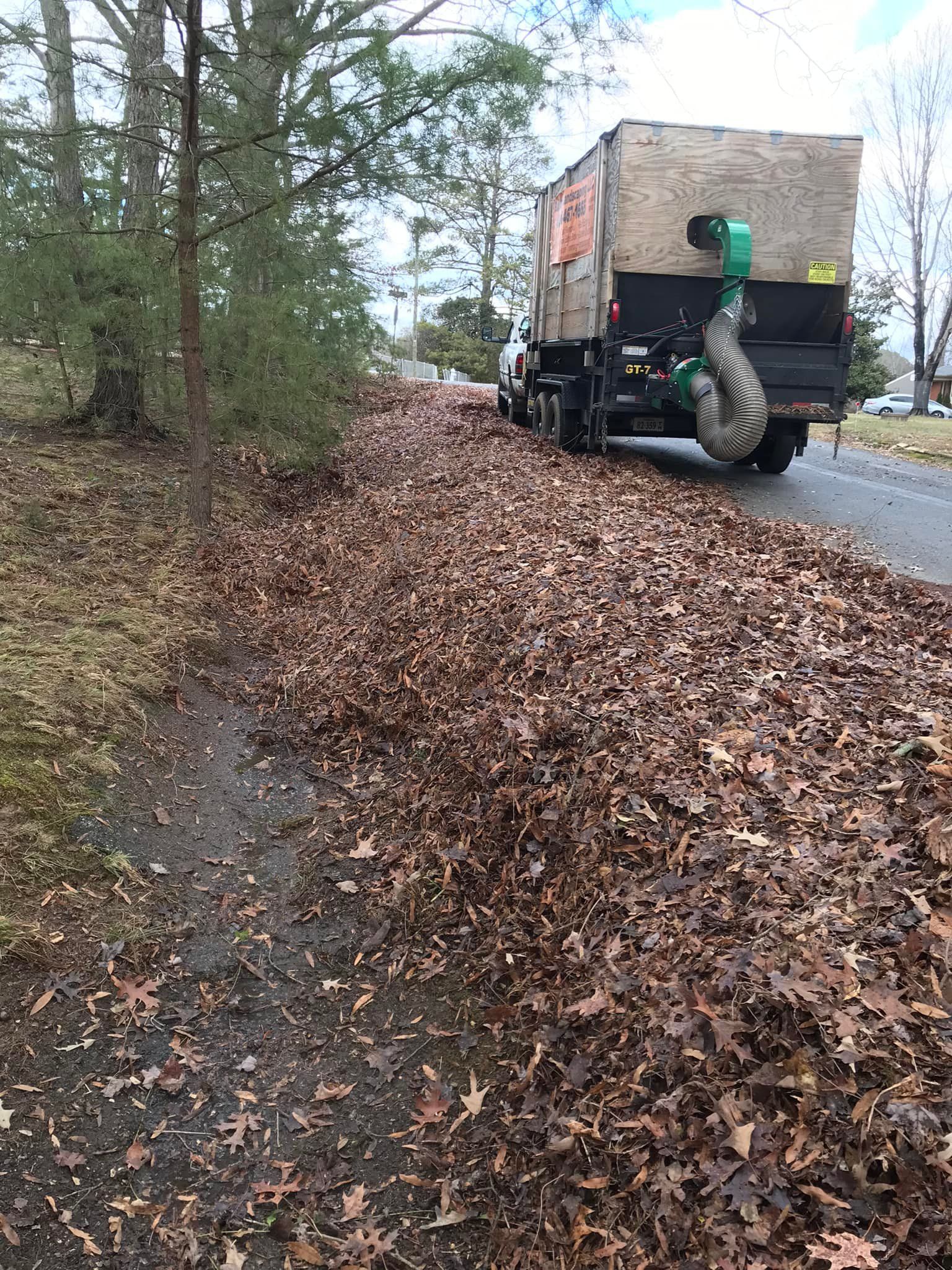 A truck is driving down a road filled with leaves.