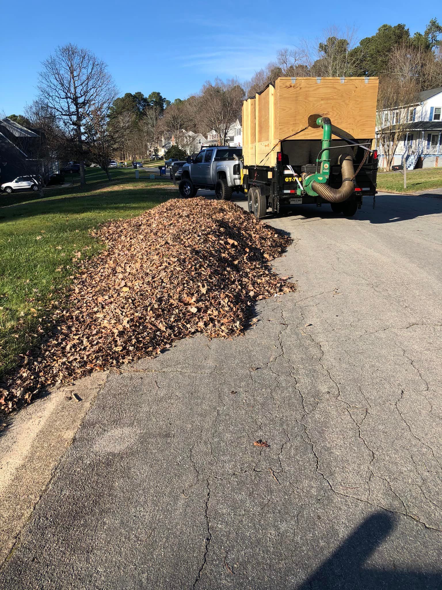 A pile of leaves is sitting on the side of a road next to a truck.