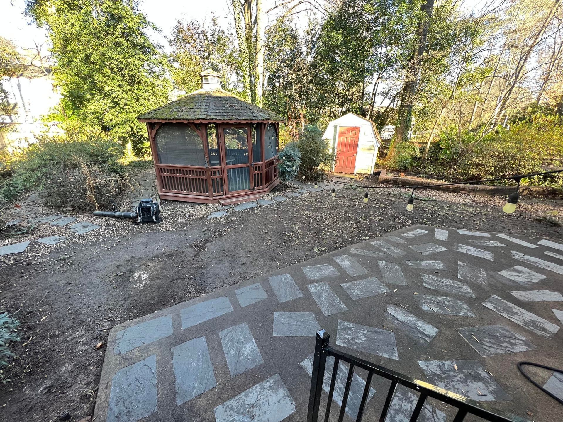 A gazebo is sitting in the middle of a backyard surrounded by trees.