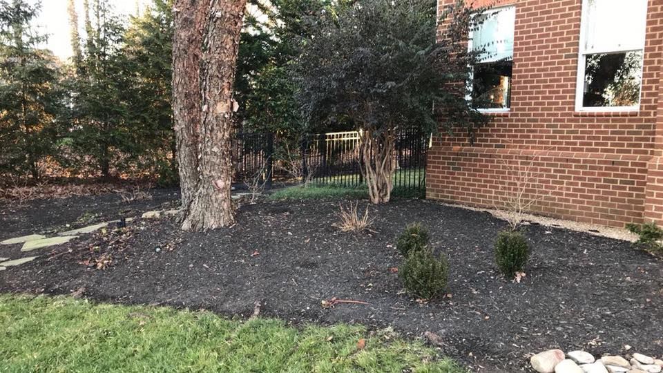 A brick house with a lush green yard and trees in front of it.