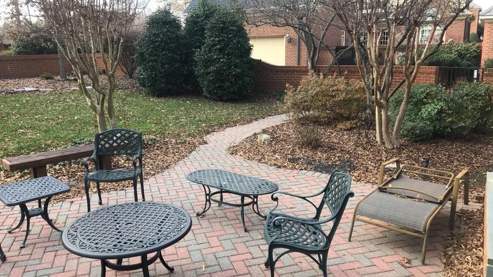 A patio with tables and chairs on a brick walkway.