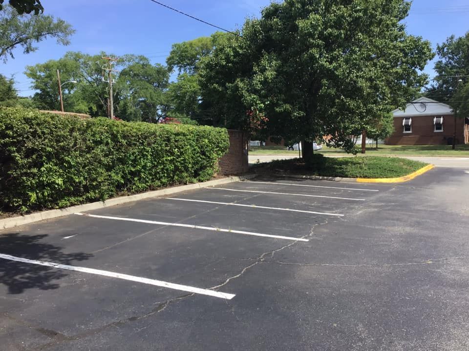 A parking lot with a tree and a house in the background