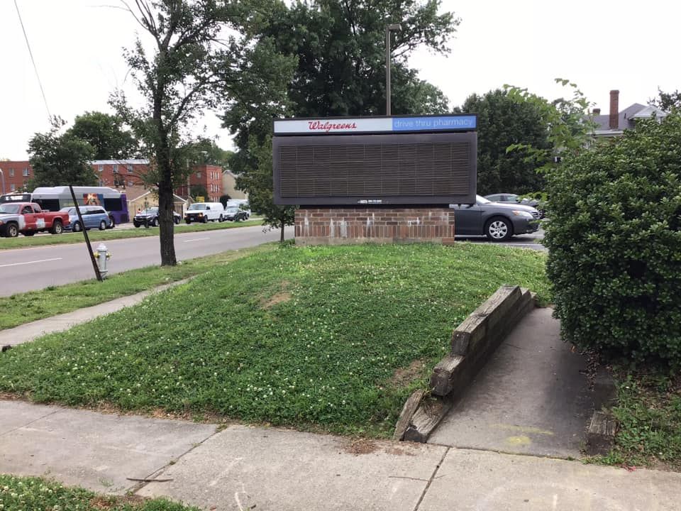 A large sign on the side of a road with a car parked in front of it