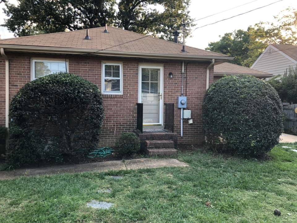 A small brick house with bushes in front of it