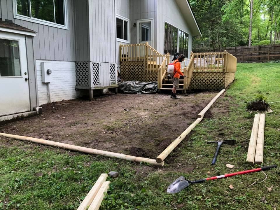 A man is working on a patio in front of a house.