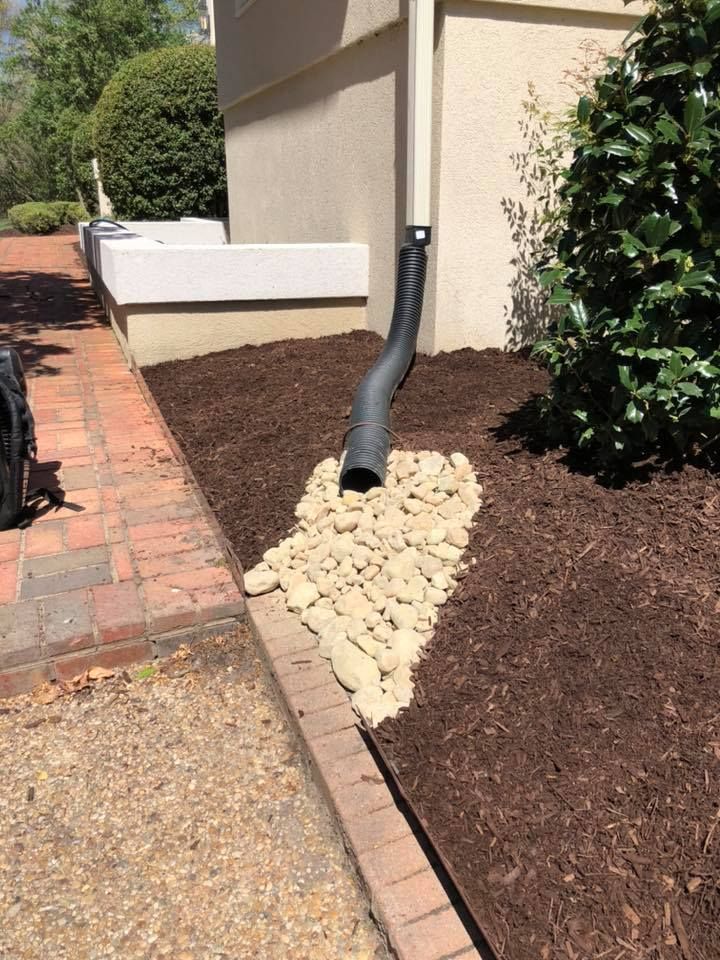 A drain pipe is sitting on top of a pile of mulch next to a house.