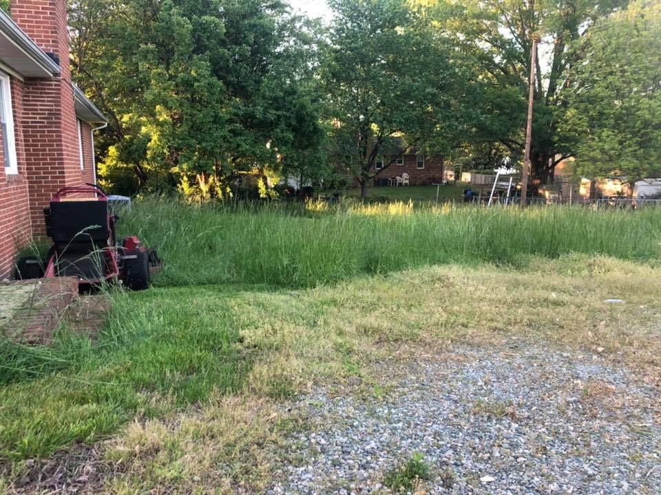 A lawn mower is sitting in the grass in front of a brick house.