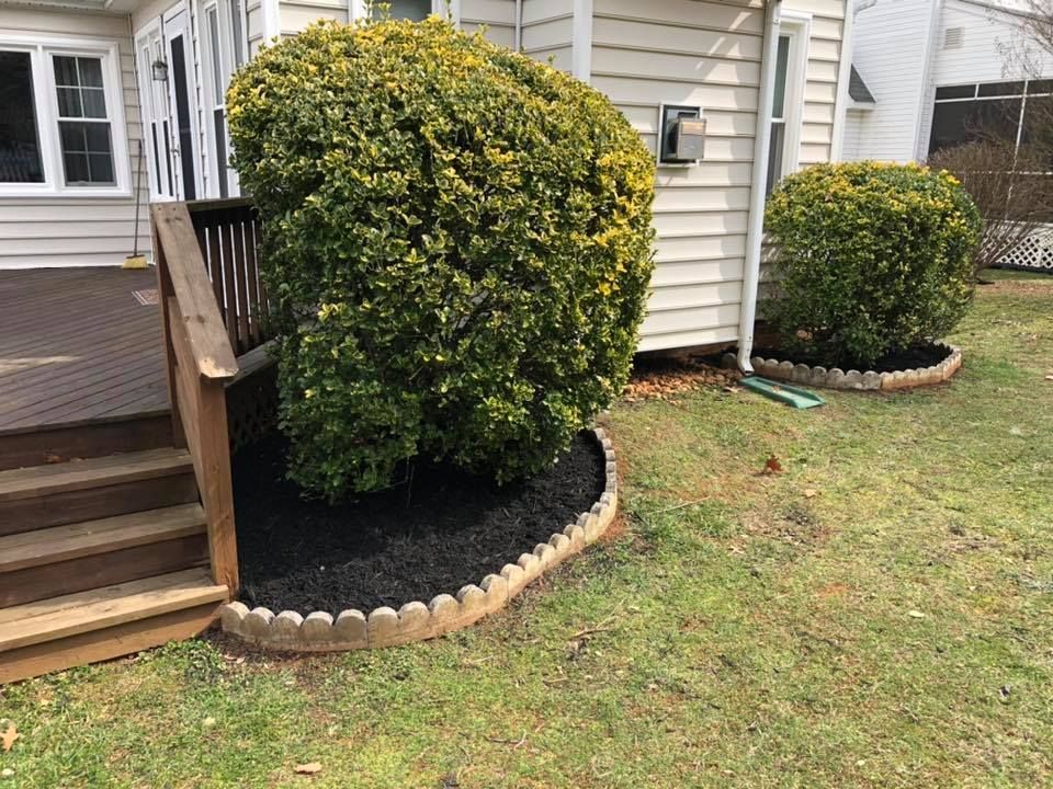A house with a deck and bushes in front of it.