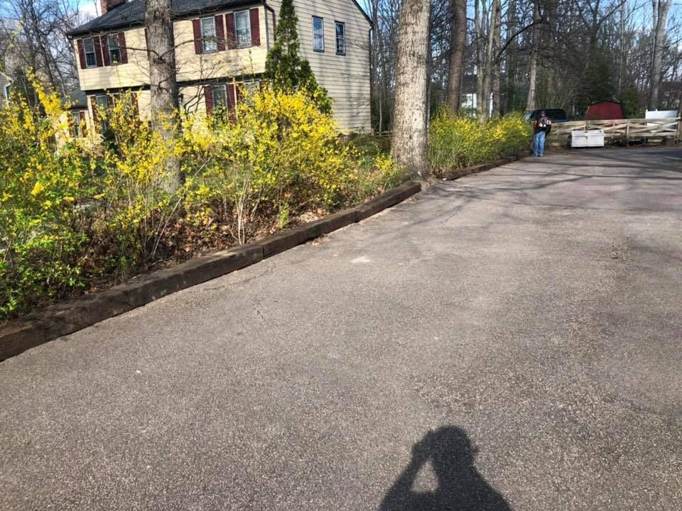 A shadow of a person is cast on the road in front of a house.