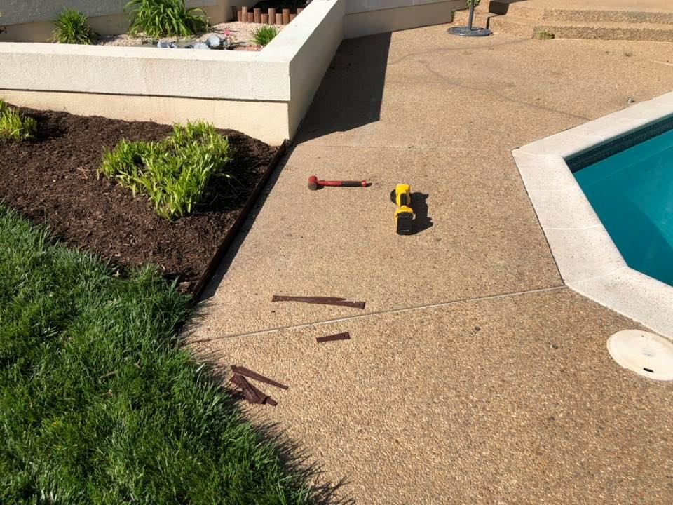 A concrete patio with a swimming pool in the background