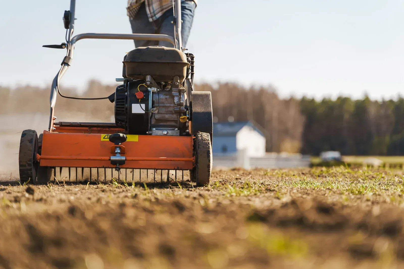 A person is using a lawn mower to cut grass in a field.