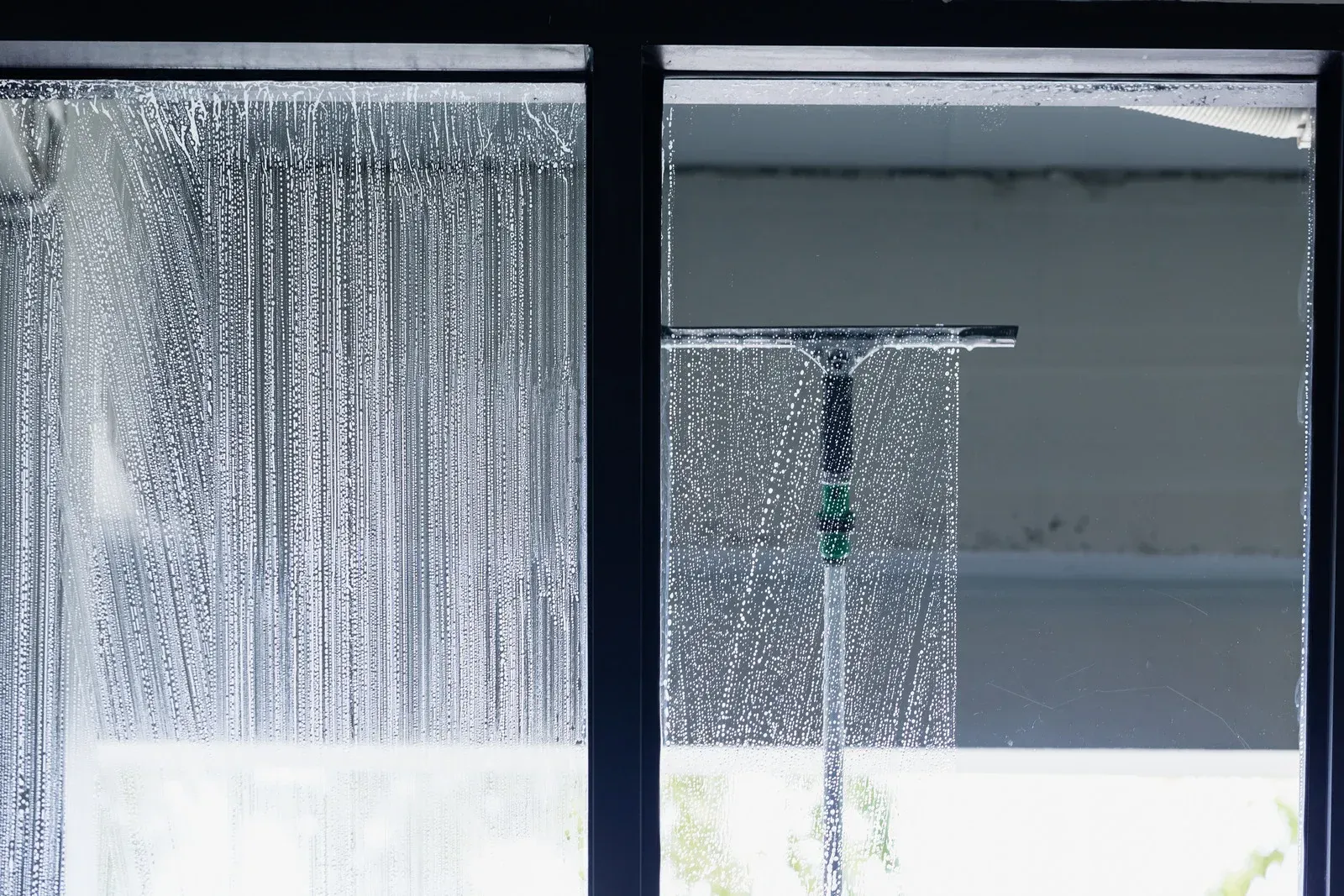 A person is cleaning a window with a squeegee.