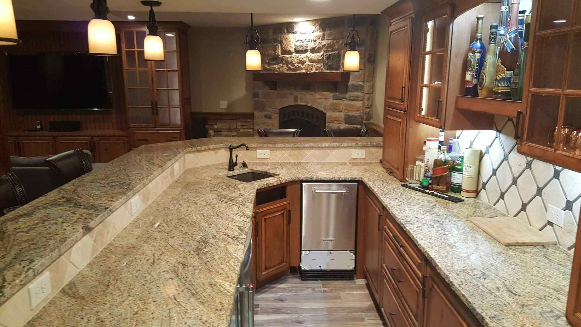 Bar area with granite countertops, stone fireplace, wood cabinets, and mini-fridge.