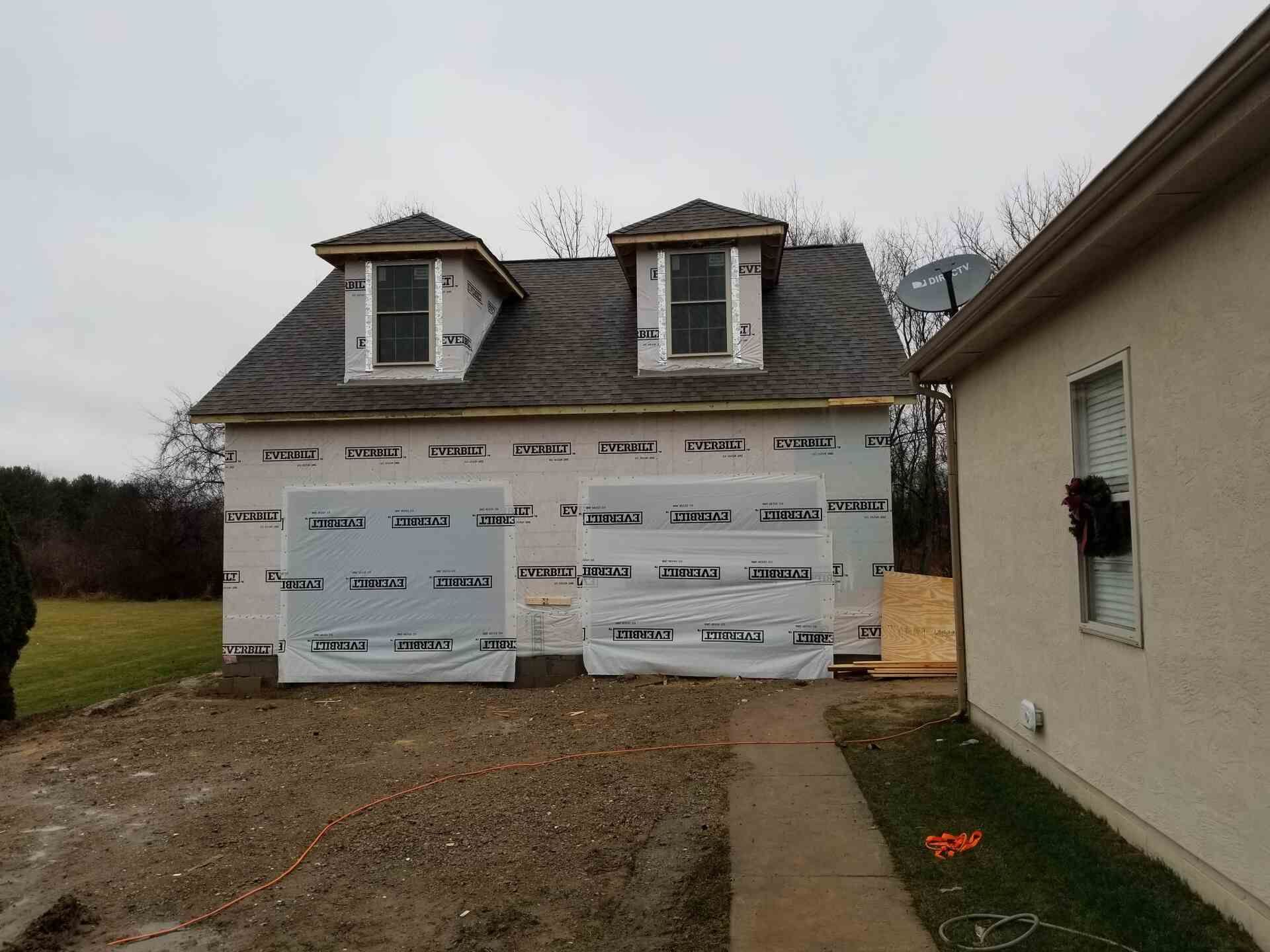 Roofers installing asphalt shingles on a residential roof; tools and materials visible.