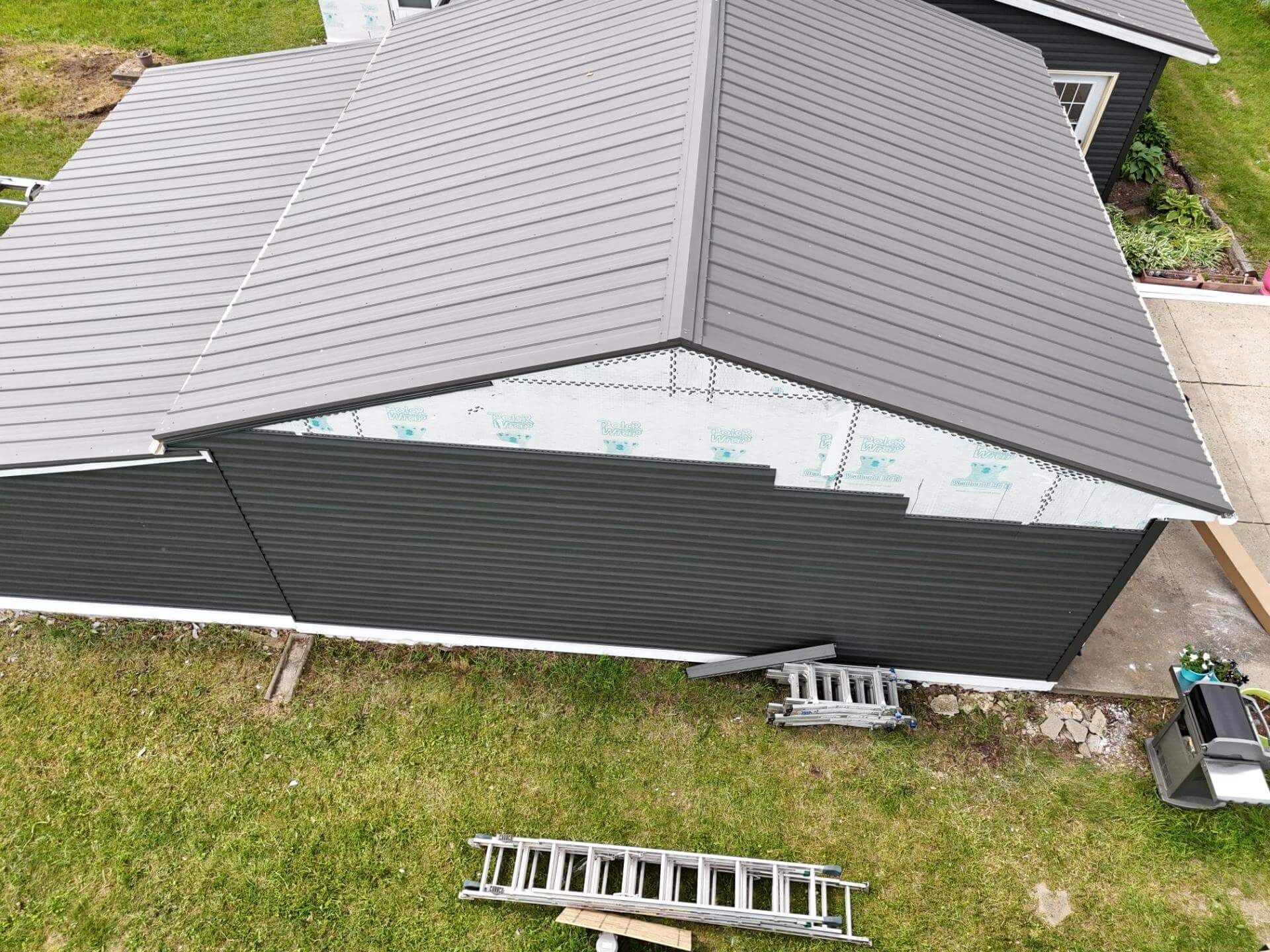 Roofers installing asphalt shingles on a residential roof; tools and materials visible.