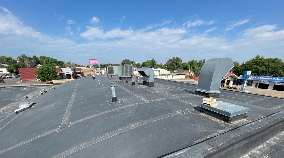 Roofers installing asphalt shingles on a residential roof; tools and materials visible.