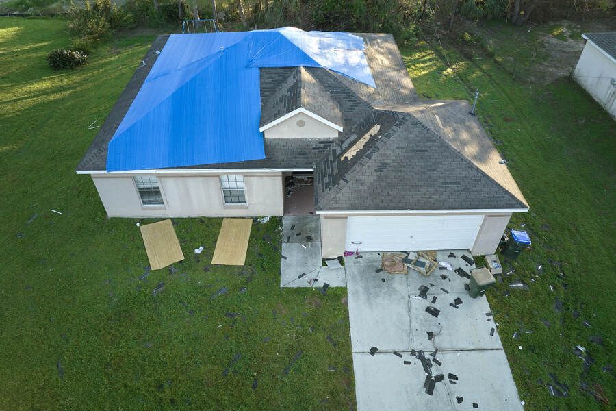 Roofers installing asphalt shingles on a residential roof; tools and materials visible.