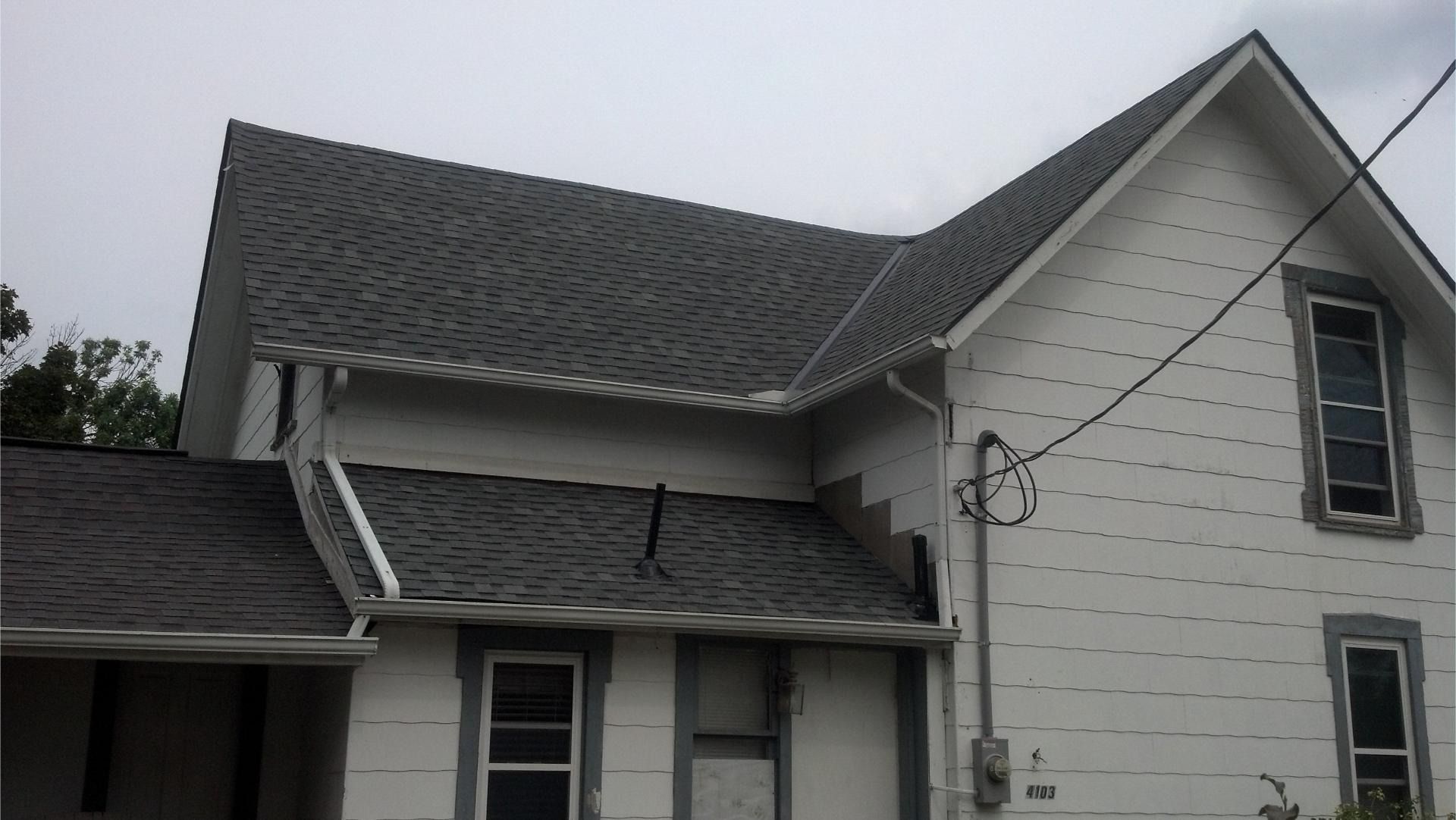 White house with dark gray roof and trim, under a cloudy sky.