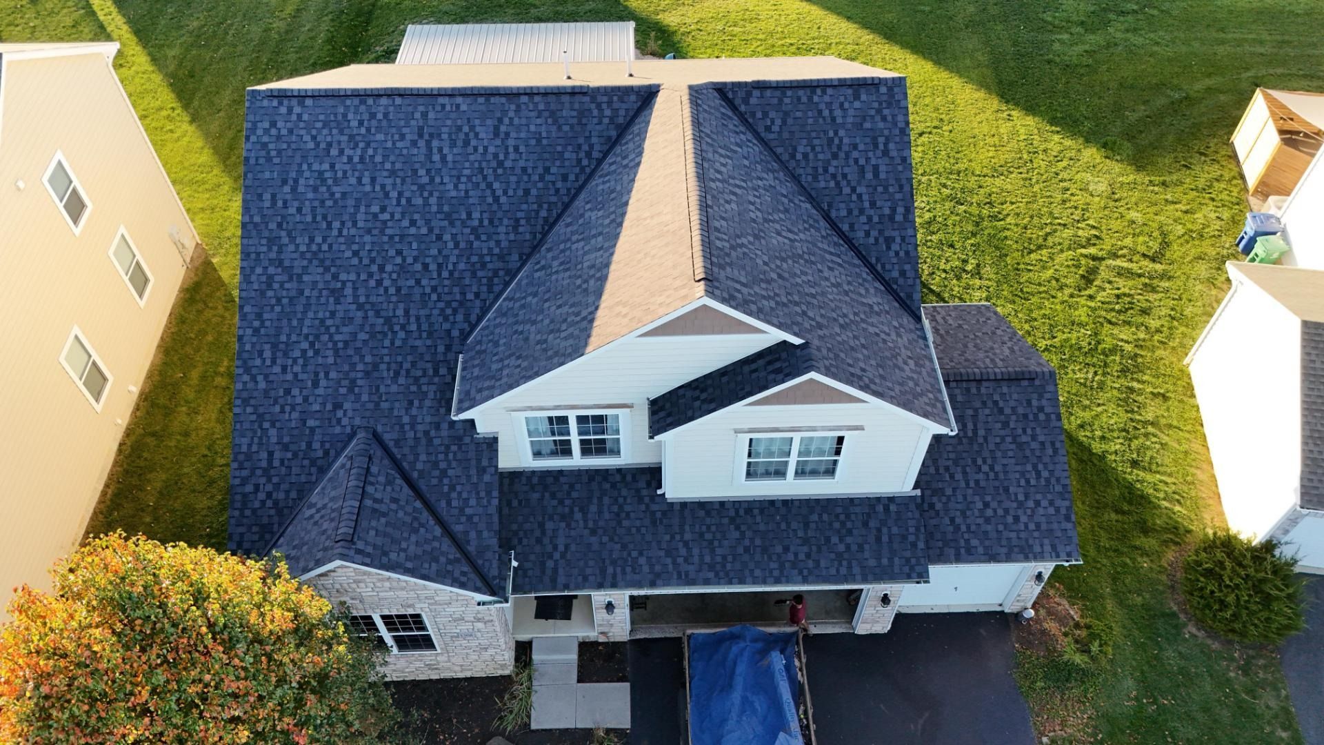 Overhead view of a house with dark blue roof, white walls, and a grassy lawn.