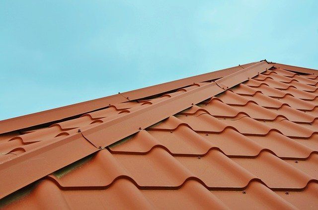 Roofers installing asphalt shingles on a residential roof; tools and materials visible.