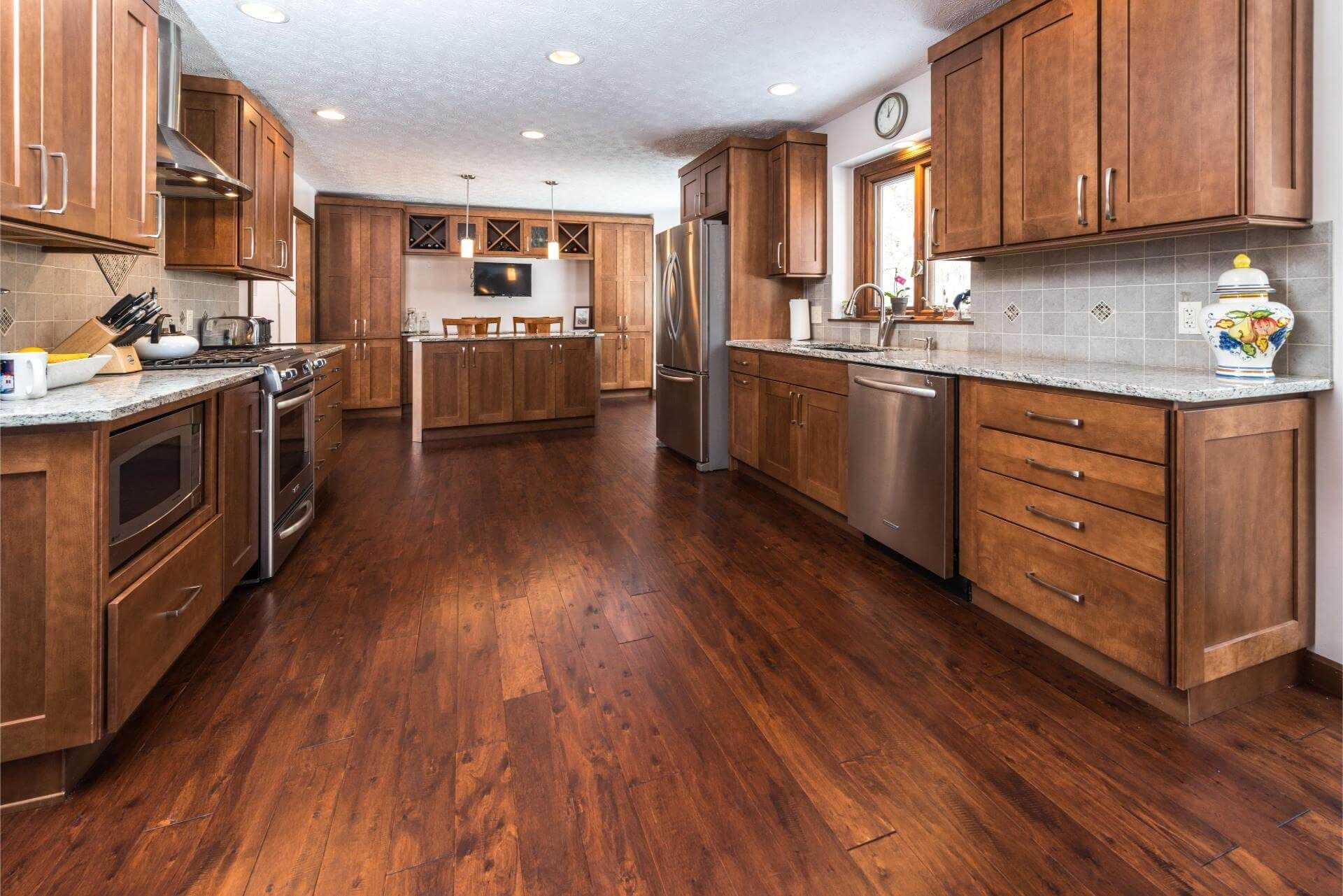 Spacious kitchen with wood cabinets, stainless steel appliances, granite countertops, and dark wood flooring.