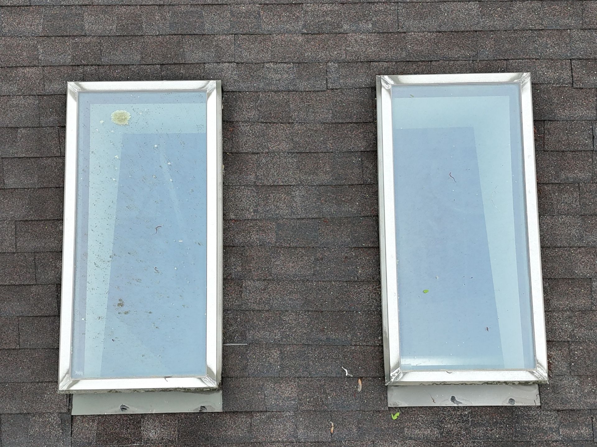 Two rectangular skylights on a dark shingle roof.