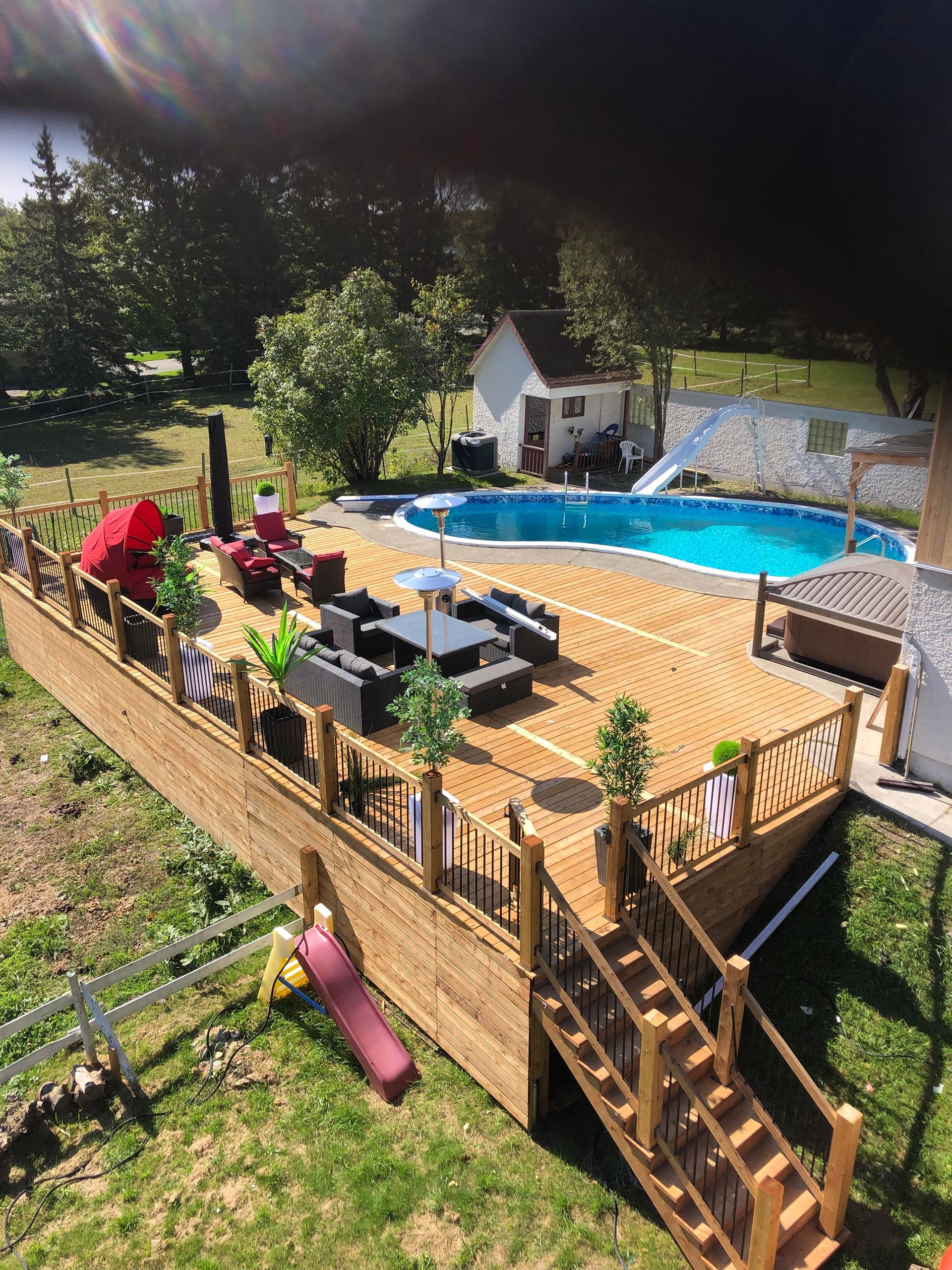 Une vue aérienne d'une grande terrasse en bois avec une piscine en arrière-plan.