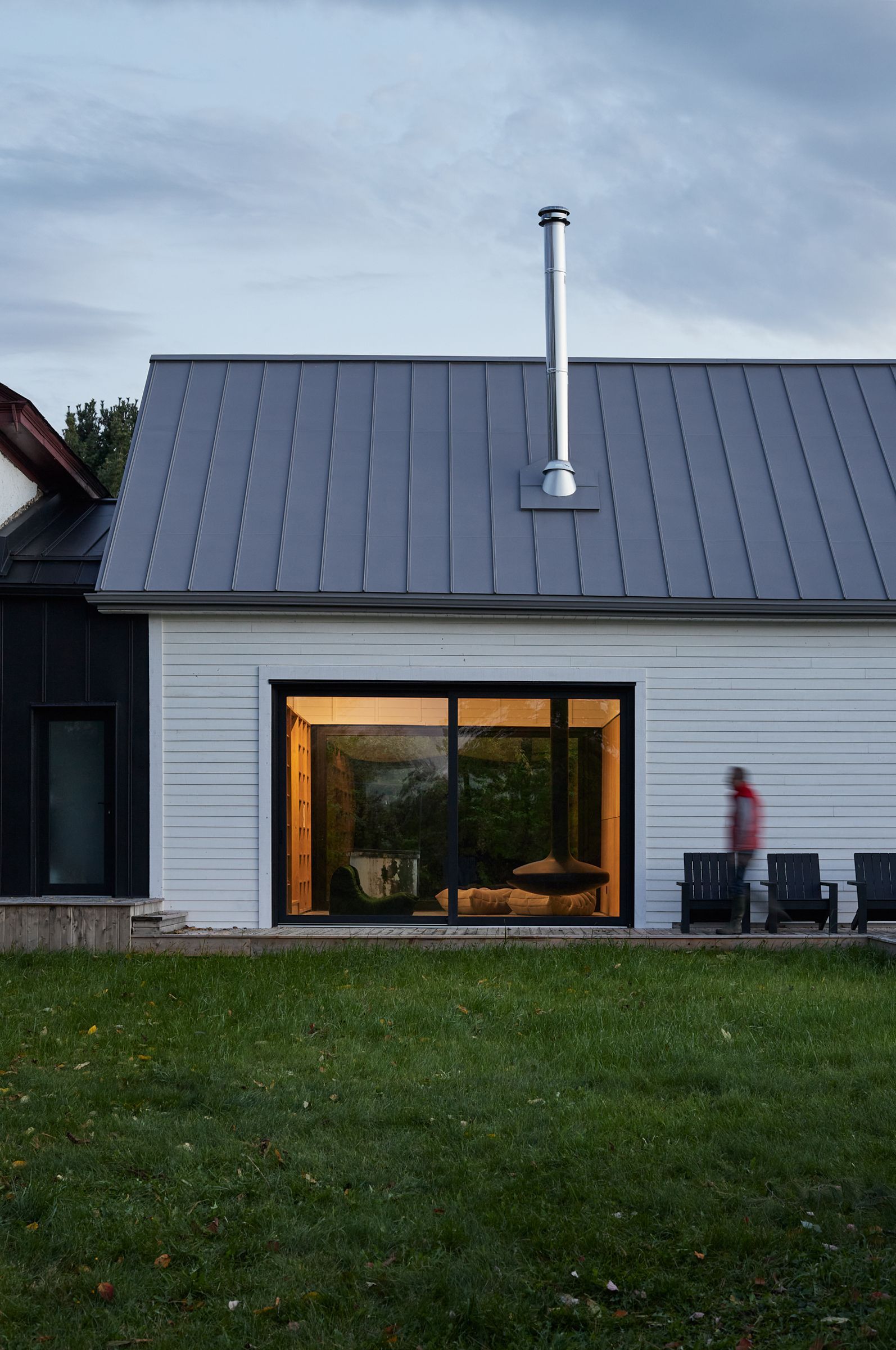 L'arrière d'une maison avec un toit gris et une grande fenêtre.