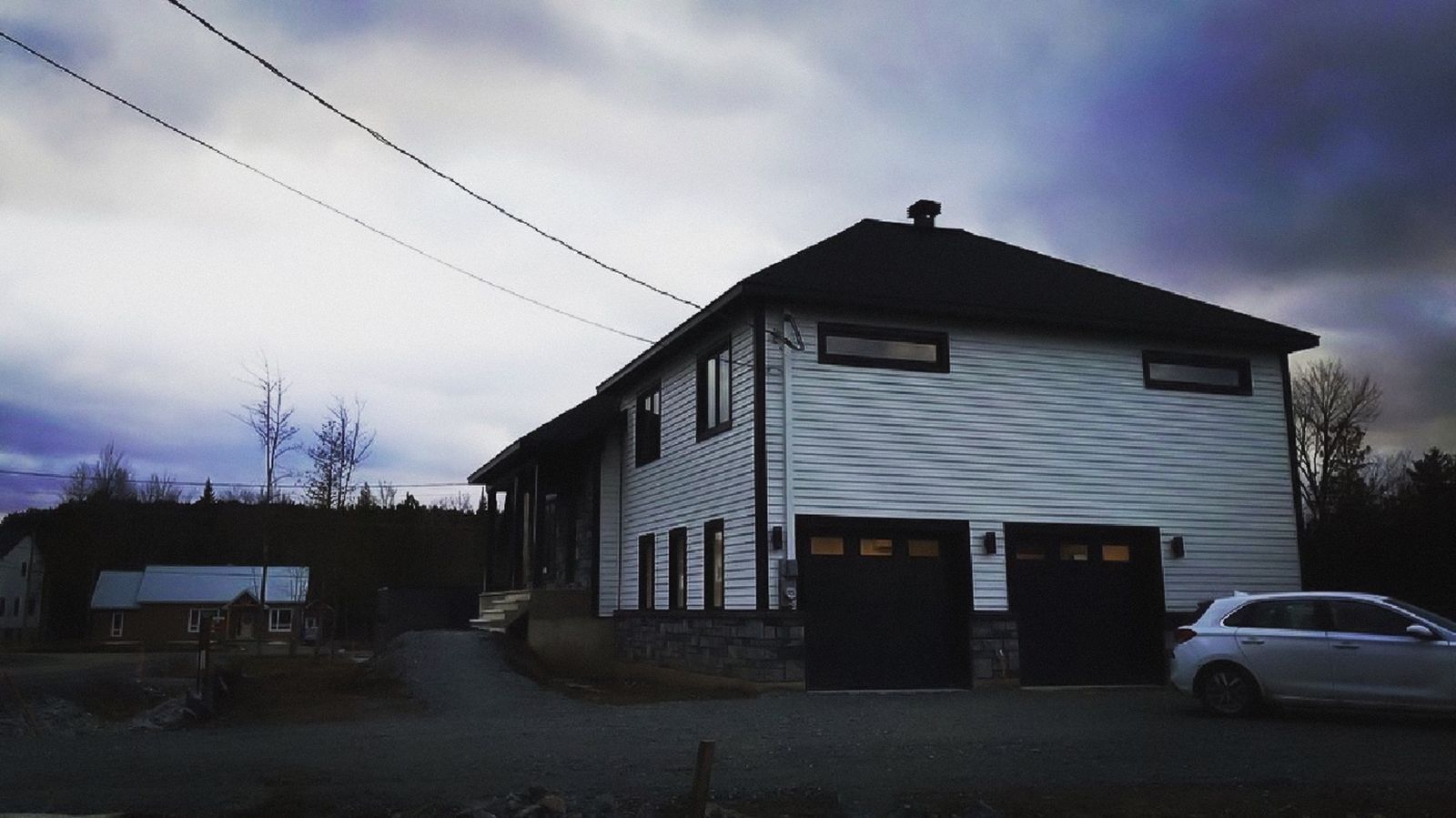Une voiture blanche est garée devant une grande maison blanche.