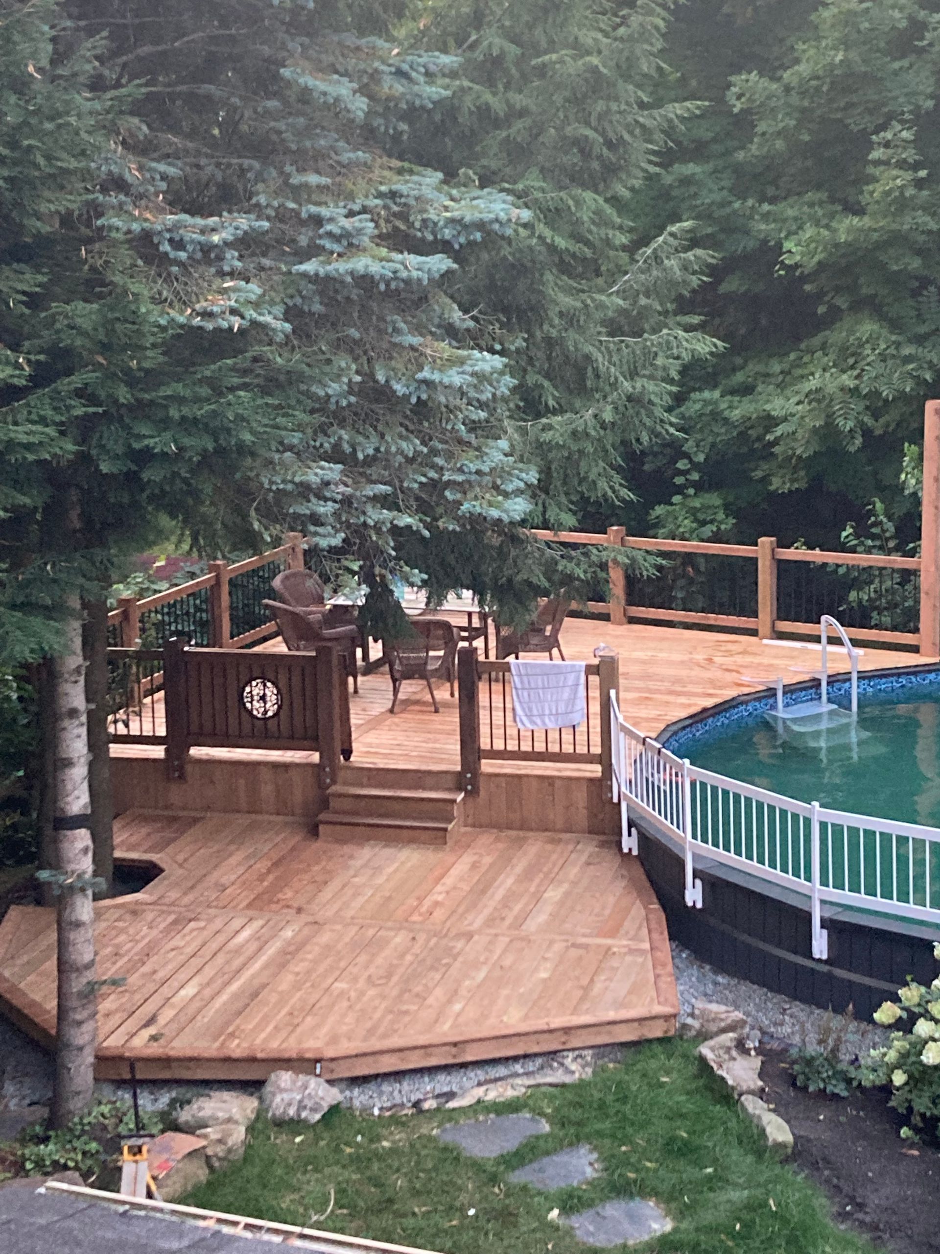 Une terrasse en bois à côté d'une piscine dans une cour arrière.