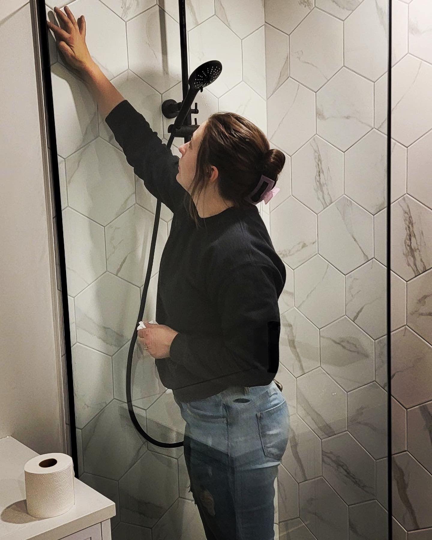 Une femme est debout dans une douche et tient une pomme de douche.