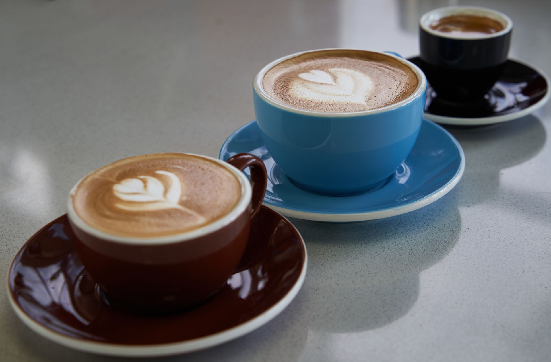 Tres tazas de café están sobre una mesa.