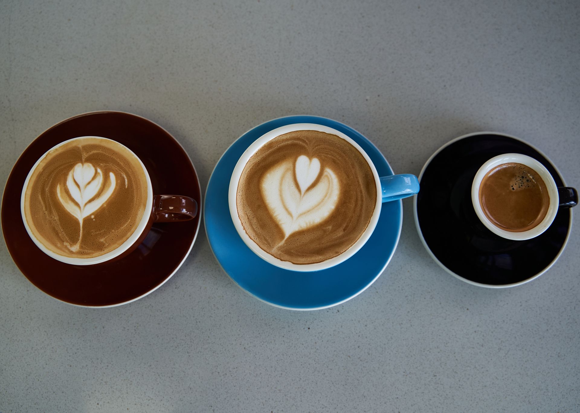 Tres tazas de café con arte latte están alineadas en fila