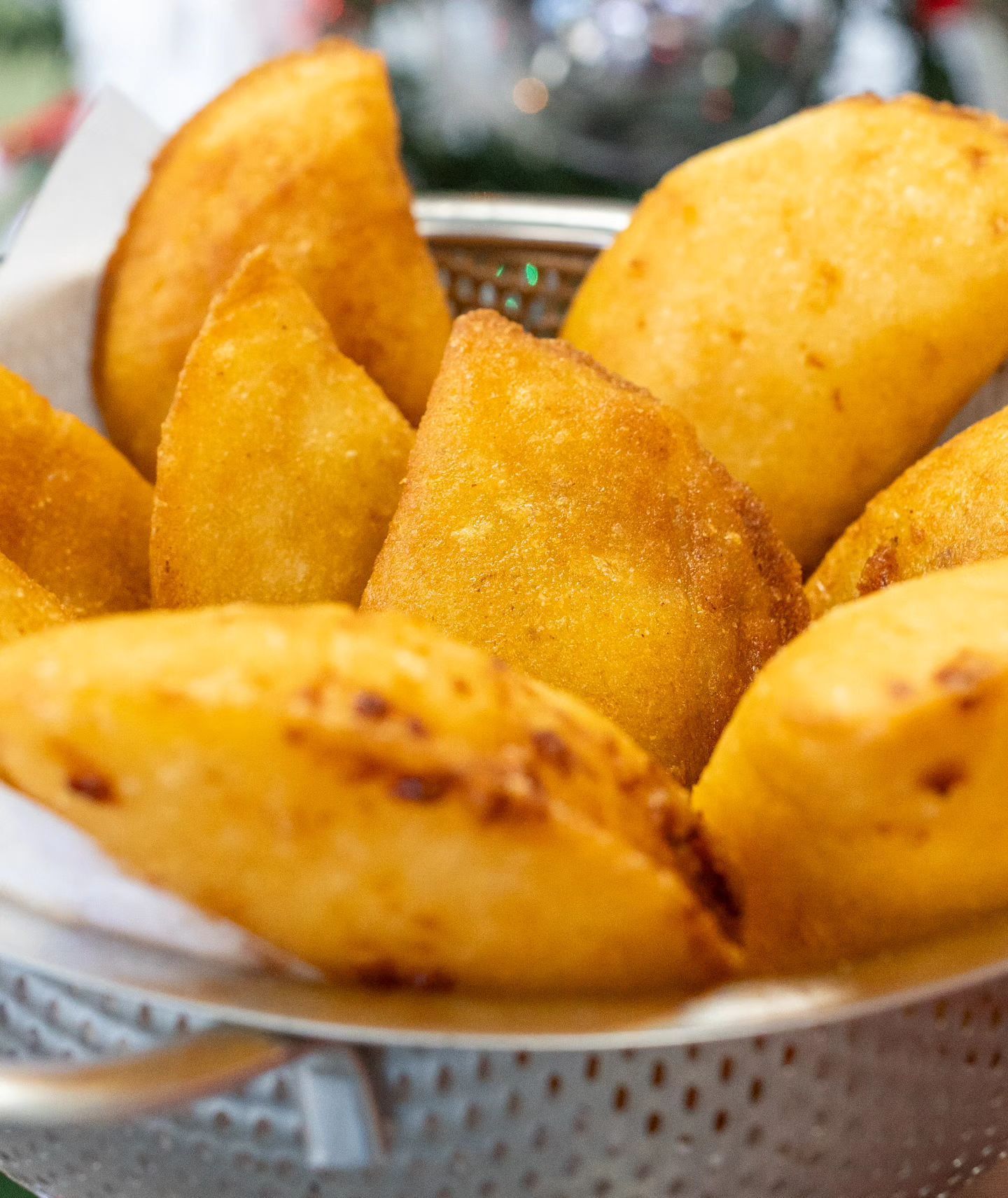 Un colador lleno de comida frita sobre una mesa.