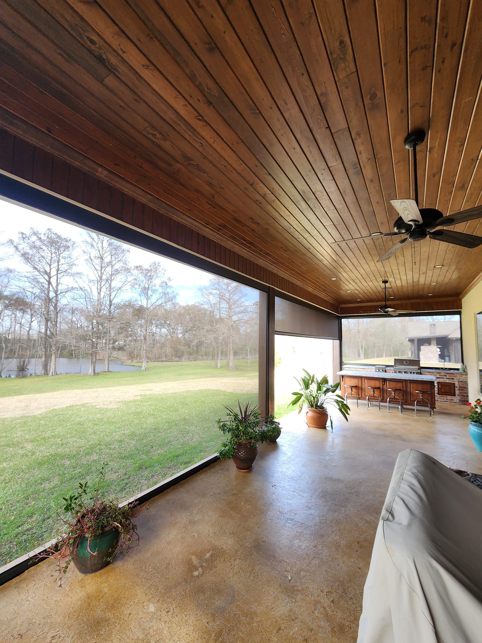 a screened in porch with a ceiling fan and a view of a field .