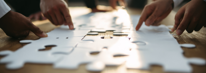 Manos de varias personas armando un rompecabezas sobre una mesa de madera.