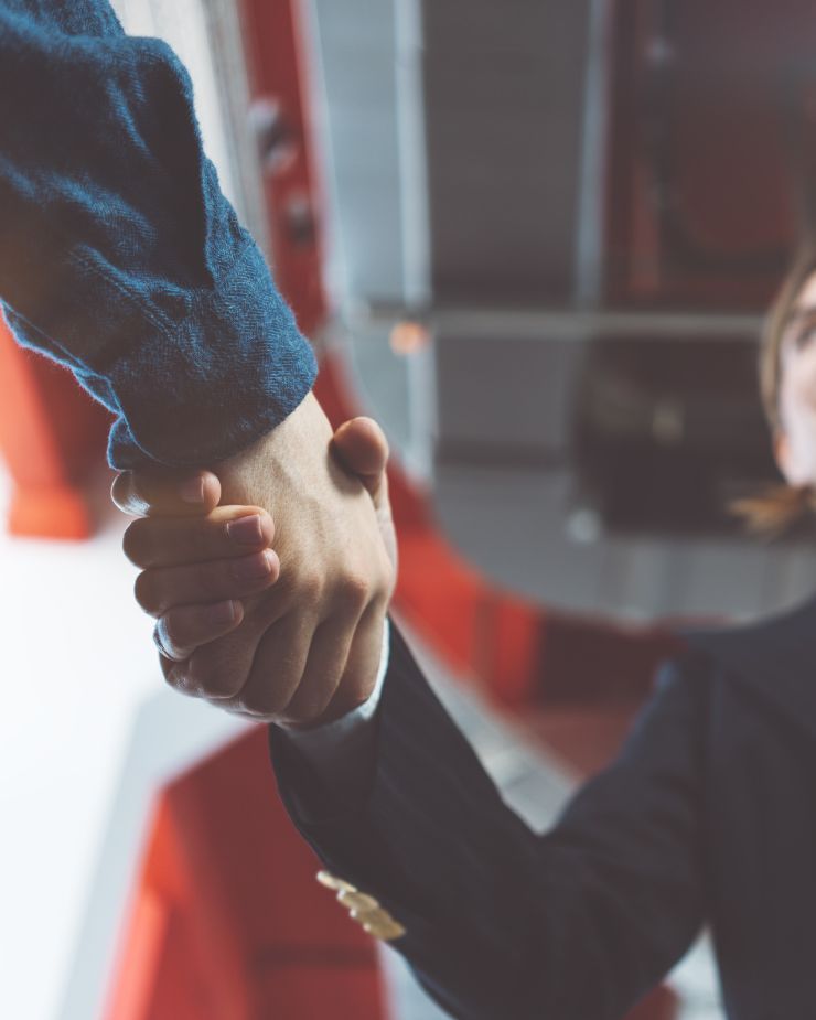 Dos personas dándose la mano, fondo borroso, acuerdo comercial.